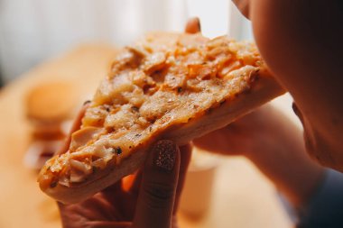 Restoranda pizza dilimi tutan bir kadın resmi.