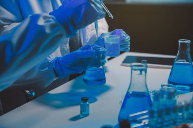 Kimyager ve bilim adamı test tüpüne kimyasal sıvı bırakıyor. Bilim araştırma ve geliştirme konsepti.