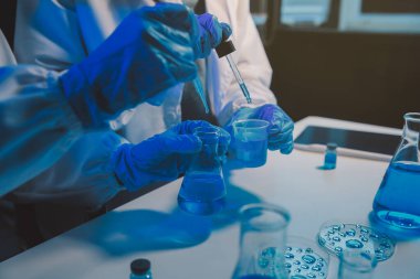 Kimyager ve bilim adamı test tüpüne kimyasal sıvı bırakıyor. Bilim araştırma ve geliştirme konsepti.