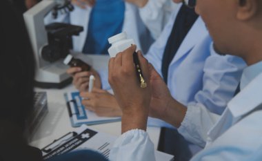 Sağlık personeli sabah toplantı odasında toplanıyor. Dijital tablete bakan doktorlar ve hemşireler.