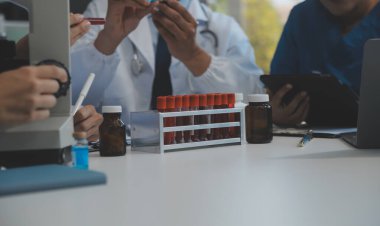 Sağlık personeli sabah toplantı odasında toplanıyor. Dijital tablete bakan doktorlar ve hemşireler.