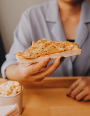 Restoranda pizza dilimi tutan bir kadın resmi.