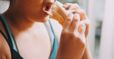 Asyalı sağlıklı bir kadın sabah sandviçle kahvaltı yapar.