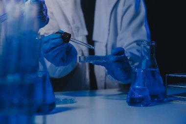 Kimyager ve bilim adamı test tüpüne kimyasal sıvı bırakıyor. Bilim araştırma ve geliştirme konsepti.