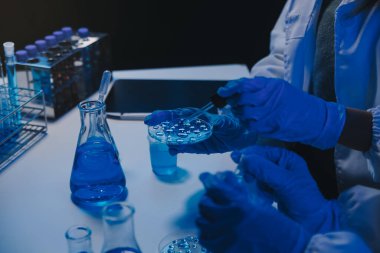 Kimyager ve bilim adamı test tüpüne kimyasal sıvı bırakıyor. Bilim araştırma ve geliştirme konsepti.