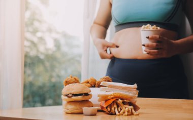 Yemek ya da değil. Burger bakarak cheerless tombul kadın yemek ya da değil düşünme