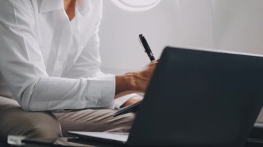 Uçakta, seyahatte ve işte dizüstü bilgisayar kullanan iş adamı