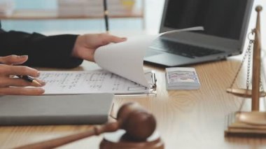 Avukat, ahşap masada dizüstü bilgisayar, tokmak ve adalet terazisiyle yeni iş sözleşmesi üzerinde çalışıyor.