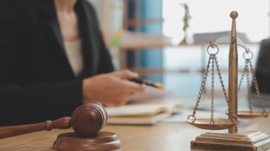 Avukat, ahşap masada dizüstü bilgisayar, tokmak ve adalet terazisiyle yeni iş sözleşmesi üzerinde çalışıyor.