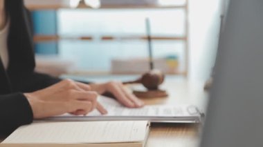 Avukat, ahşap masada dizüstü bilgisayar, tokmak ve adalet terazisiyle yeni iş sözleşmesi üzerinde çalışıyor.