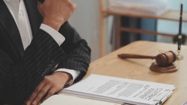 Avukat, ahşap masada dizüstü bilgisayar, tokmak ve adalet terazisiyle yeni iş sözleşmesi üzerinde çalışıyor.