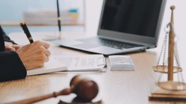Avukat, ahşap masada dizüstü bilgisayar, tokmak ve adalet terazisiyle yeni iş sözleşmesi üzerinde çalışıyor.