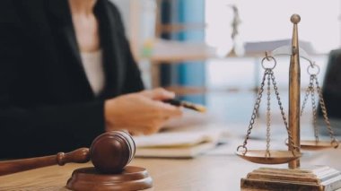 Avukat, ahşap masada dizüstü bilgisayar, tokmak ve adalet terazisiyle yeni iş sözleşmesi üzerinde çalışıyor.