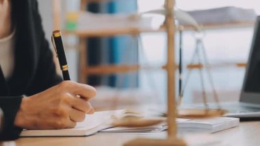 Avukat, ahşap masada dizüstü bilgisayar, tokmak ve adalet terazisiyle yeni iş sözleşmesi üzerinde çalışıyor.