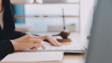 Avukat, ahşap masada dizüstü bilgisayar, tokmak ve adalet terazisiyle yeni iş sözleşmesi üzerinde çalışıyor.