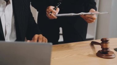 Takım elbiseli genç bir adam dizüstü bilgisayar tutuyor.