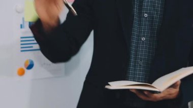 Bir çizelge tutan işadamı tahtadaki grafiğe işaret ediyor..