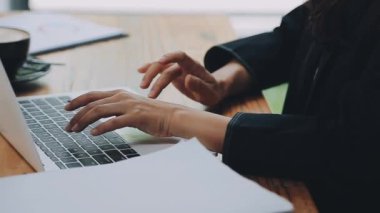 Genç bayan girişimci modern ofisteki ahşap masada belgelerle çalışıyor.