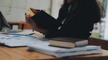 Modern ofiste belgelerle çalışan genç bir iş kadını.