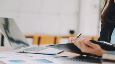 Modern ofiste belgelerle çalışan genç bir iş kadını.