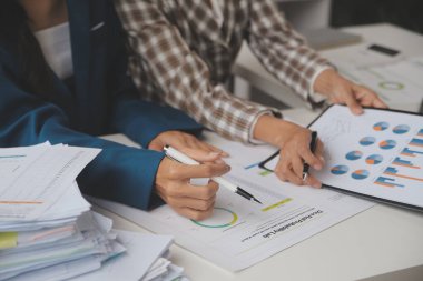 Group of confident business people point to graphs and charts to analyze market data, balance sheet, account, net profit to plan new sales strategies to increase production capacity.