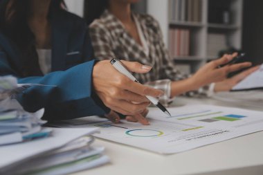 Group of confident business people point to graphs and charts to analyze market data, balance sheet, account, net profit to plan new sales strategies to increase production capacity.