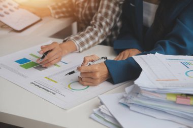 Group of confident business people point to graphs and charts to analyze market data, balance sheet, account, net profit to plan new sales strategies to increase production capacity.