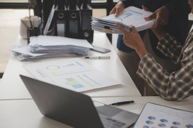 Group of confident business people point to graphs and charts to analyze market data, balance sheet, account, net profit to plan new sales strategies to increase production capacity.