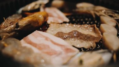 Geleneksel Yakiniku yemek stillerini kullanarak et ve karides ızgarası yapan insanların yakın çekim görüntüsü