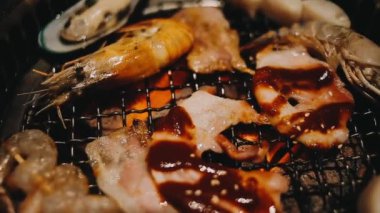 Geleneksel Yakiniku yemek stillerini kullanarak et ve karides ızgarası yapan insanların yakın çekim görüntüsü