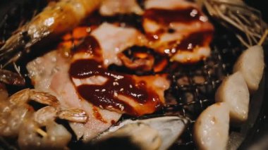 Geleneksel Yakiniku yemek stillerini kullanarak et ve karides ızgarası yapan insanların yakın çekim görüntüsü