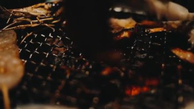 Geleneksel Yakiniku yemek stillerini kullanarak et ve karides ızgarası yapan insanların yakın çekim görüntüsü