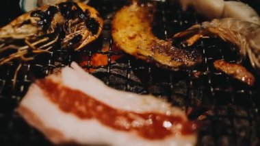 Geleneksel Yakiniku yemek stillerini kullanarak et ve karides ızgarası yapan insanların yakın çekim görüntüsü