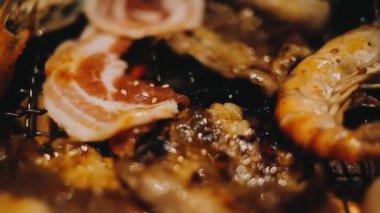 Geleneksel Yakiniku yemek stillerini kullanarak et ve karides ızgarası yapan insanların yakın çekim görüntüsü