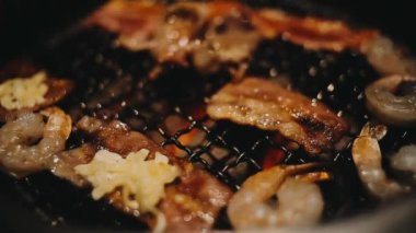 Sığır eti ve deniz ürünleri ızgarası yapan insanların yakınındaki manzara. Japonya 'da birçok insan Yakiniku denilen bu yemek yapma tarzını sever.
