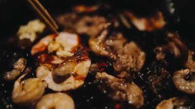 Sığır eti ve deniz ürünleri ızgarası yapan insanların yakınındaki manzara. Japonya 'da birçok insan Yakiniku denilen bu yemek yapma tarzını sever.