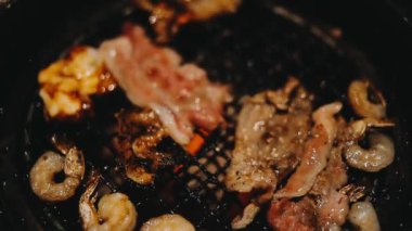 Sığır eti ve deniz ürünleri ızgarası yapan insanların yakınındaki manzara. Japonya 'da birçok insan Yakiniku denilen bu yemek yapma tarzını sever.