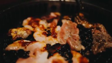 Izgarada et ve karides pişiren insanların yakın çekim görüntüsü. Yakiniku, Japonya 'da yemek yemenin çok popüler bir yoludur..