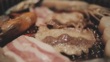 Izgarada et ve karides pişiren insanların yakın çekim görüntüsü. Yakiniku, Japonya 'da yemek yemenin çok popüler bir yoludur..