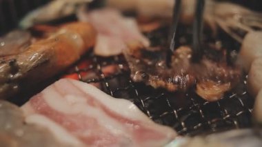 Izgarada et ve karides pişiren insanların yakın çekim görüntüsü. Yakiniku, Japonya 'da yemek yemenin çok popüler bir yoludur..