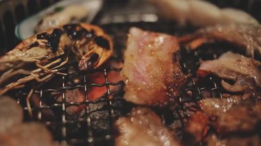 Masa başı ızgarasında deniz ürünleri ve sığır eti hazırlayan lokantaların detaylı görüntüleri. Yakiniku olarak bilinen bu Japon barbekü metodu, sevilen bir aşçılık geleneğidir..