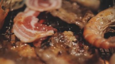 Masa başı ızgarasında deniz ürünleri ve sığır eti hazırlayan lokantaların detaylı görüntüleri. Yakiniku olarak bilinen bu Japon barbekü metodu, sevilen bir aşçılık geleneğidir..