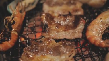 Masa başı ızgarasında deniz ürünleri ve sığır eti hazırlayan lokantaların detaylı görüntüleri. Yakiniku olarak bilinen bu Japon barbekü metodu, sevilen bir aşçılık geleneğidir..