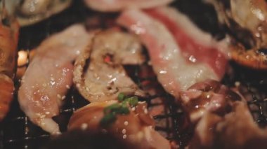 Masa başı ızgarasında deniz ürünleri ve sığır eti hazırlayan lokantaların detaylı görüntüleri. Yakiniku olarak bilinen bu Japon barbekü metodu, sevilen bir aşçılık geleneğidir..