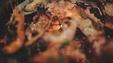 Masa başı ızgarasında deniz ürünleri ve sığır eti hazırlayan lokantaların detaylı görüntüleri. Yakiniku olarak bilinen bu Japon barbekü metodu, sevilen bir aşçılık geleneğidir..
