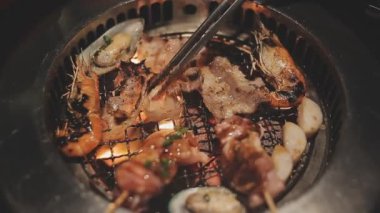 Masa başı ızgarasında deniz ürünleri ve sığır eti hazırlayan lokantaların detaylı görüntüleri. Yakiniku olarak bilinen bu Japon barbekü metodu, sevilen bir aşçılık geleneğidir..