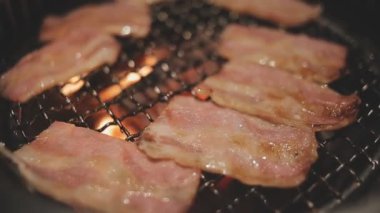 Mutfak meraklılarının et ve kabukluların bir karışımını hazırladığı yakın görüş. Yakiniku, Japonya 'nın sevilen masa başı ızgara geleneği interaktif gastronomiyi özetliyor.