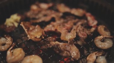 İnsanların ızgara et ve karides pişirmesini yakından izliyoruz. Yakiniku, Japonya 'nın en popüler yemek pişirme tarzlarından biridir..