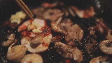 İnsanların ızgara et ve karides pişirmesini yakından izliyoruz. Yakiniku, Japonya 'nın en popüler yemek pişirme tarzlarından biridir..