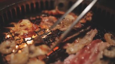 İnsanların ızgara et ve karides pişirmesini yakından izliyoruz. Yakiniku, Japonya 'nın en popüler yemek pişirme tarzlarından biridir..